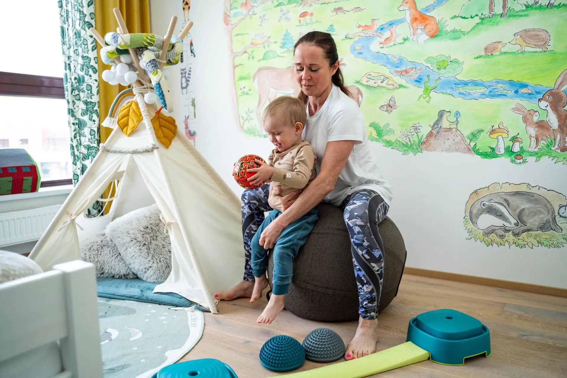 Dětská fyzioterapeutka cvičí s dítětem doma formou hry